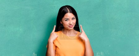 Photo for Pretty latin woman with a bad attitude looking proud and aggressive, pointing upwards or making fun sign with hands - Royalty Free Image