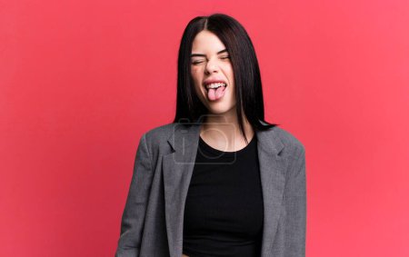Foto de Young adult pretty woman with cheerful, carefree, rebellious attitude, joking and sticking tongue out, having fun - Imagen libre de derechos