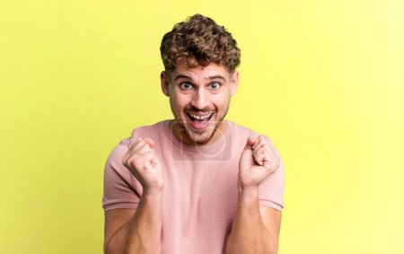 Téléchargez les photos : Young adult caucasian man feeling shocked, excited and happy, laughing and celebrating success, saying wow! - en image libre de droit