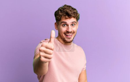Téléchargez les photos : Young adult caucasian man feeling proud, carefree, confident and happy, smiling positively with thumbs up - en image libre de droit