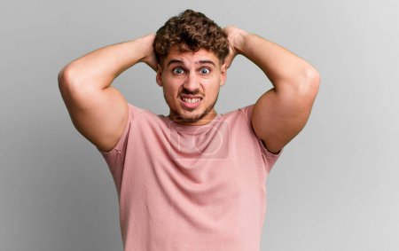 Téléchargez les photos : Young adult caucasian man feeling stressed, worried, anxious or scared, with hands on head, panicking at mistake - en image libre de droit