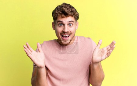 Photo pour Young adult caucasian man feeling happy, excited, surprised or shocked, smiling and astonished at something unbelievable - image libre de droit