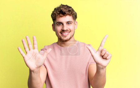 Téléchargez les photos : Young adult caucasian man smiling and looking friendly, showing number seven or seventh with hand forward, counting down - en image libre de droit