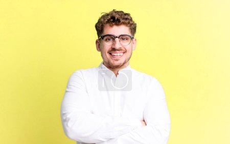 Téléchargez les photos : Young adult caucasian man looking like a happy, proud and satisfied achiever smiling with arms crossed - en image libre de droit
