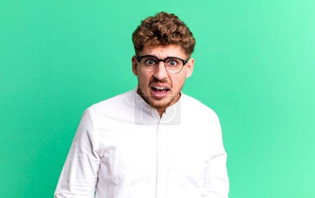 Photo for Young adult caucasian man feeling terrified and shocked, with mouth wide open in surprise - Royalty Free Image