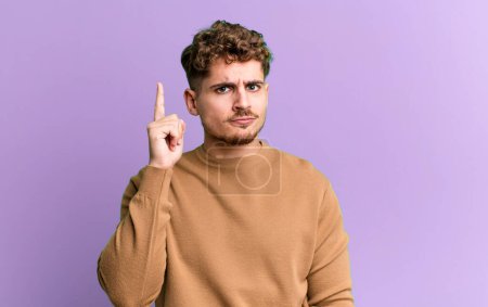Photo for Young adult caucasian man feeling like a genius holding finger proudly up in the air after realizing a great idea, saying eureka - Royalty Free Image