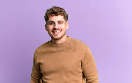 Photo for Young adult caucasian man smiling cheerfully and casually with a positive, happy, confident and relaxed expression - Royalty Free Image