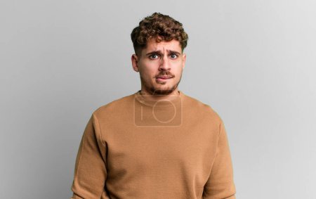 Photo for Young adult caucasian man feeling clueless, confused and uncertain about which option to pick, trying to solve the problem - Royalty Free Image