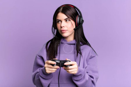 Photo for Young gamer woman with a headset and a contoller - Royalty Free Image