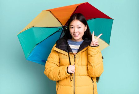 Photo for Young adult pretty asian woman wearing anorak and an umbrella. winter and cold concept - Royalty Free Image
