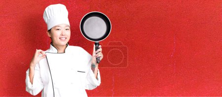 Téléchargez les photos : Jeune adulte jolie femme asiatique. chef de restaurant avec une poêle - en image libre de droit