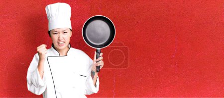 Foto de Joven adulto bastante asiático mujer. chef de restaurante con una sartén - Imagen libre de derechos