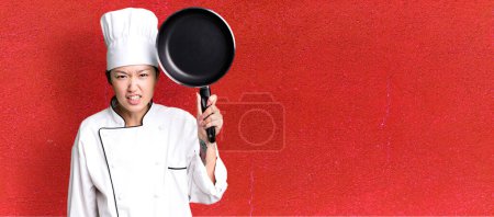 Foto de Joven adulto bastante asiático mujer. chef de restaurante con una sartén - Imagen libre de derechos