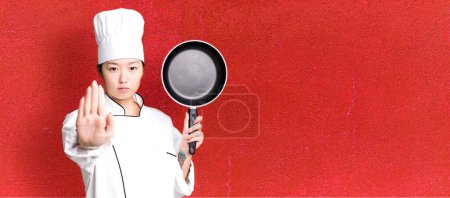 Photo for Young adult pretty asian woman. restaurant chef with a frying pan - Royalty Free Image