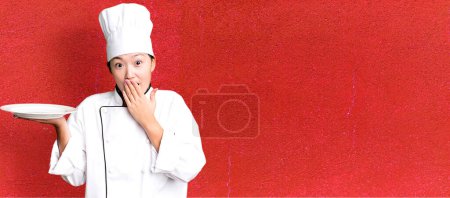 Foto de Joven adulto bastante asiático mujer. chef del restaurante sosteniendo un plato vacío - Imagen libre de derechos