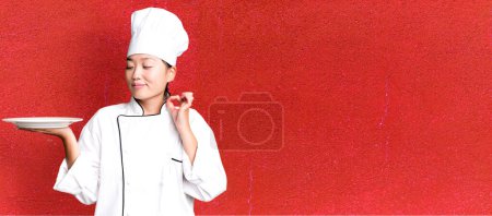 Téléchargez les photos : Jeune adulte jolie femme asiatique. chef restaurant tenant un plat vide - en image libre de droit