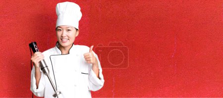 Photo for Young adult pretty asian woman. restaurant chef with a hand blender - Royalty Free Image