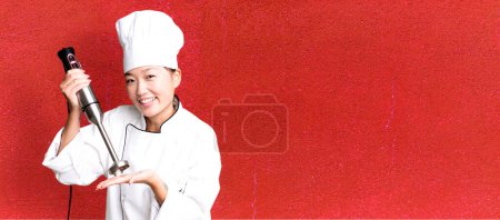 Photo for Young adult pretty asian woman. restaurant chef with a hand blender - Royalty Free Image