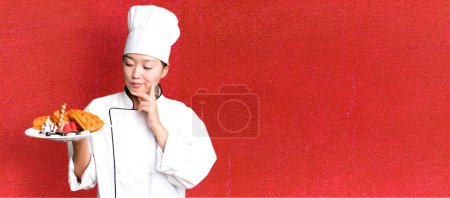 Téléchargez les photos : Jeune adulte jolie femme asiatique. chef restaurant avec gaufres pour le petit déjeuner - en image libre de droit