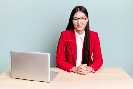 Photo for Pretty asian woman smiling happily with a hand on hip and confident. business desk concept - Royalty Free Image