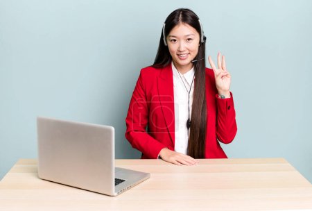Photo for Pretty asian woman smiling and looking friendly, showing number three. business desk concept - Royalty Free Image