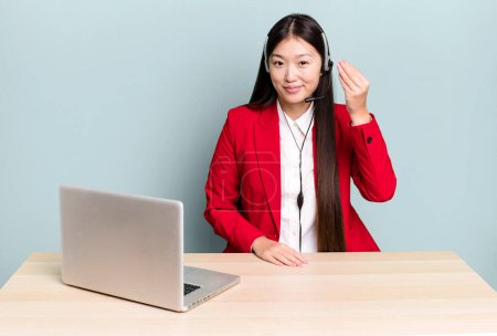 Foto de Pretty asian woman making capice or money gesture, telling you to pay. business desk concept - Imagen libre de derechos