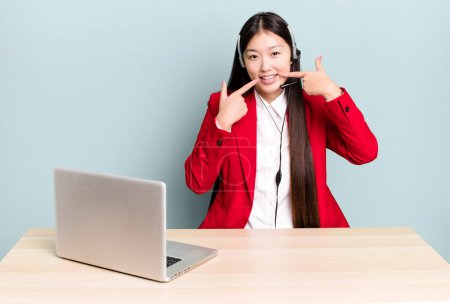 Foto de Bonita mujer asiática sonriendo con confianza señalando a su propia sonrisa amplia. concepto de escritorio de negocios - Imagen libre de derechos