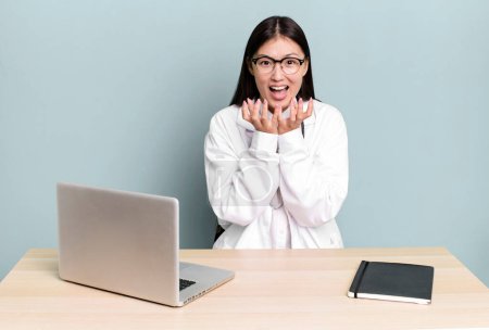 Photo for Pretty asian woman looking desperate, frustrated and stressed. physician desk and laptop - Royalty Free Image