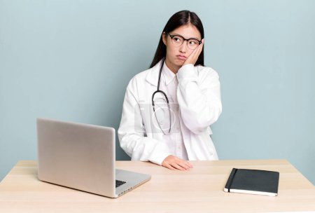 Téléchargez les photos : Pretty asian woman feeling bored, frustrated and sleepy after a tiresome. physician desk and laptop - en image libre de droit