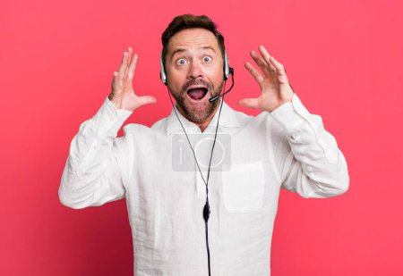 Photo for Middle age man screaming with hands up in the air. telemarketer concept - Royalty Free Image