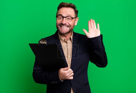 Photo for Middle age man smiling happily, waving hand, welcoming and greeting you with an inventory. business concept - Royalty Free Image