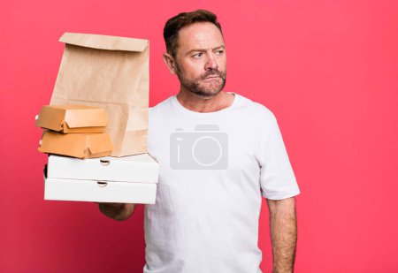Foto de Hombre de mediana edad sintiéndose triste, molesto o enojado y mirando hacia un lado. entrega y comida rápida para llevar concepto - Imagen libre de derechos