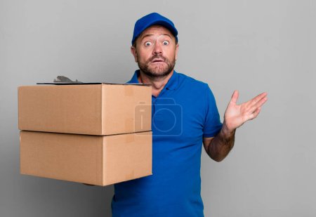 Photo for Middle age man feeling puzzled and confused and doubting. paker delivery man. packer delivery man - Royalty Free Image