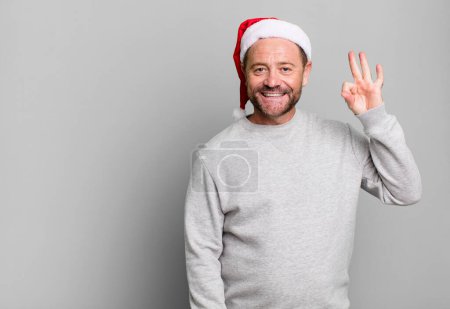 Téléchargez les photos : Homme d'âge moyen se sentant heureux, montrant l'approbation avec le geste correct. concept de Noël - en image libre de droit