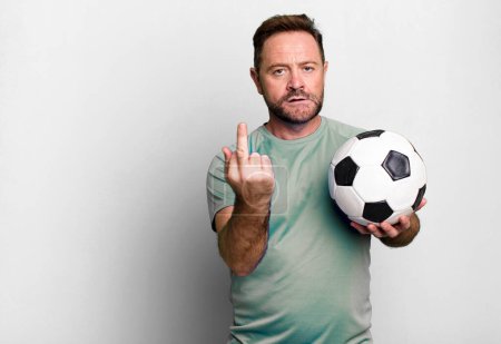 Foto de Hombre de mediana edad sintiéndose enojado, molesto, rebelde y agresivo. con una pelota de fútbol. concepto de fitness - Imagen libre de derechos