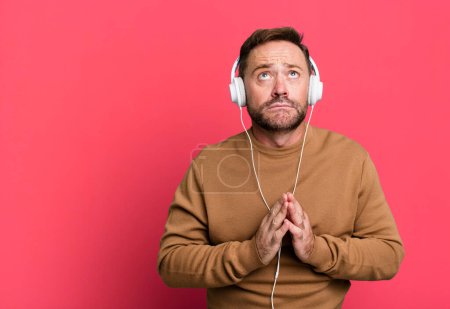 Téléchargez les photos : Homme d'âge moyen écouter de la musique avec son casque sport coach concept avec un ballon de football - en image libre de droit