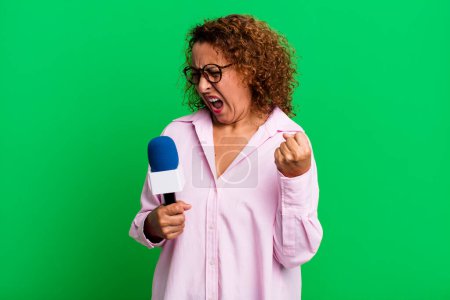 Photo for Pretty middle age woman looking unhappy and stressed, suicide gesture making gun sign. tv presenter with a microphone concept - Royalty Free Image