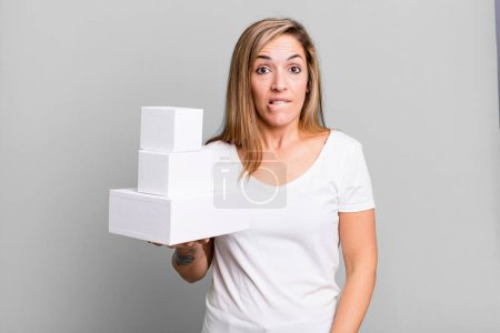 Téléchargez les photos : Pretty blonde woman looking puzzled and confused. set of different packagings - en image libre de droit