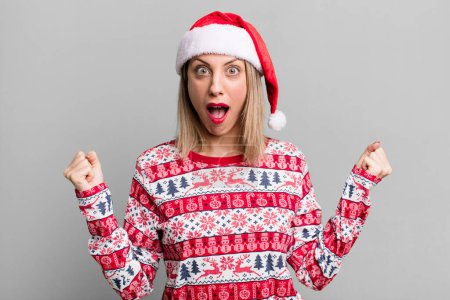 Photo for Pretty blonde woman shouting aggressively with an angry expression. christmas and santa hat concept - Royalty Free Image