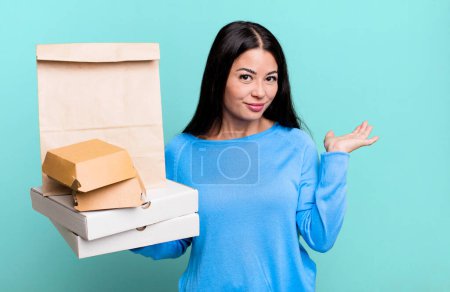 Photo for Hispanic pretty woman feeling puzzled and confused and doubting. with take away fast food packages - Royalty Free Image