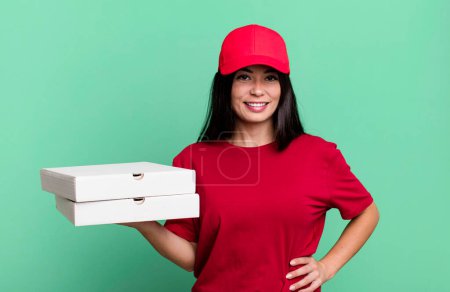 Photo for Hispanic pretty woman smiling happily with a hand on hip and confident. delivery pizza concept - Royalty Free Image