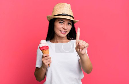 Foto de Hispanic pretty woman smiling and looking friendly, showing number one. ice cream and summer concept - Imagen libre de derechos