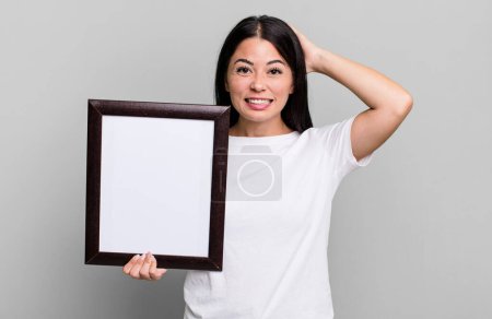 Photo for Hispanic pretty woman feeling stressed, anxious or scared, with hands on head with an empty blank frame - Royalty Free Image