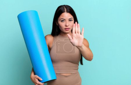 Téléchargez les photos : Hispanic pretty woman looking serious showing open palm making stop gesture yoga concept - en image libre de droit