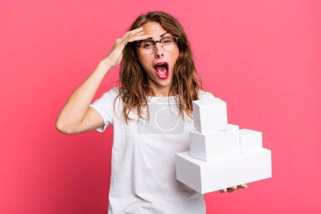 Photo for Hispanic pretty woman looking happy, astonished and surprised. with white boxes packages - Royalty Free Image