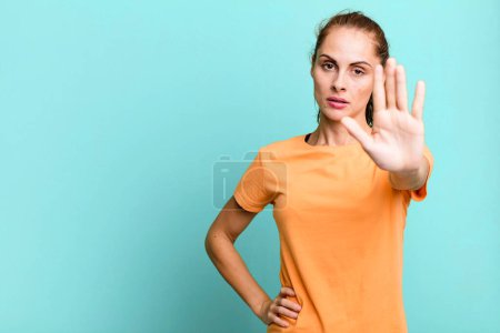 Foto de Mujer bonita hispana mirando serio mostrando la palma abierta haciendo gesto de parada. copia espacio concepto - Imagen libre de derechos