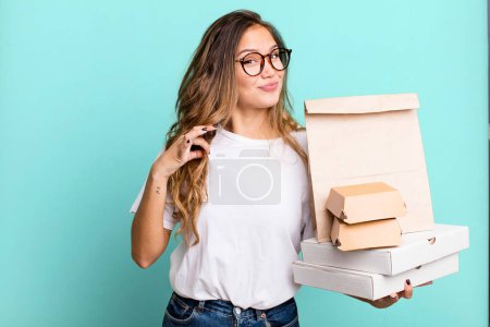 Photo for Hispanic pretty woman looking arrogant, successful, positive and proud. with fast food packages - Royalty Free Image