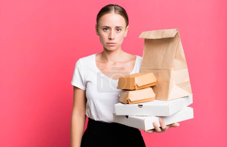 Téléchargez les photos : Caucasian pretty woman feeling sad, upset or angry and looking to the side. with fast food packages. delivery concept - en image libre de droit