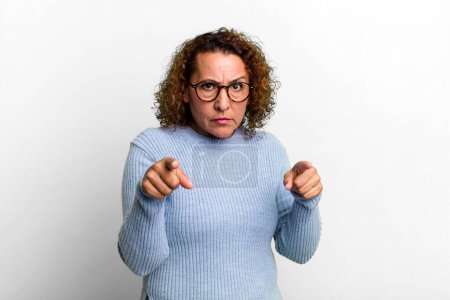 Téléchargez les photos : Femme hispanique d'âge moyen pointant vers l'avant à la caméra avec les deux doigts et l'expression en colère, vous disant de faire votre devoir - en image libre de droit