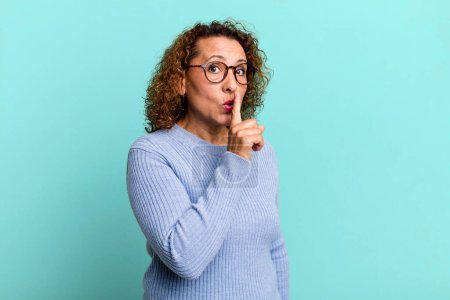 Photo for Middle age hispanic woman asking for silence and quiet, gesturing with finger in front of mouth, saying shh or keeping a secret - Royalty Free Image